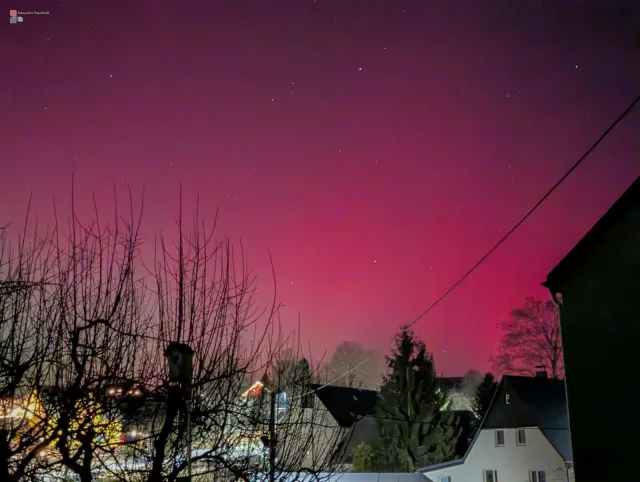 Red and green aurora rise quietly above the village and fade like an afterimage of the Sun into the night sky.
