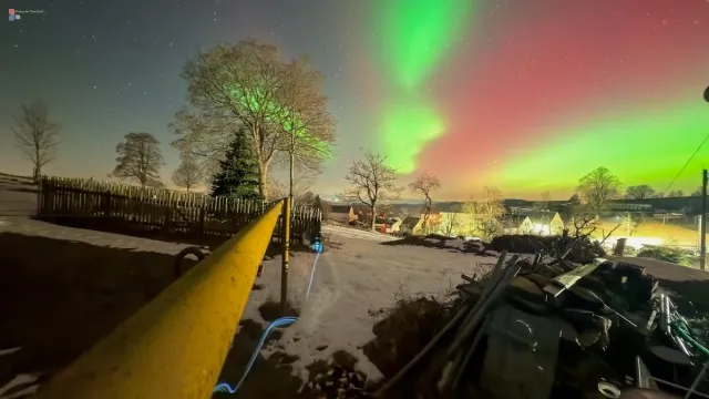 A yellow pipeline leads through the night — above it, the aurora dances as if it came from a different order.