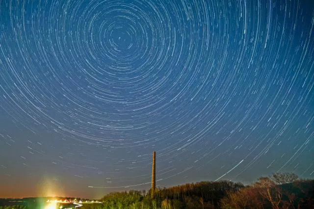 Startrails über einem Industrieschornstein