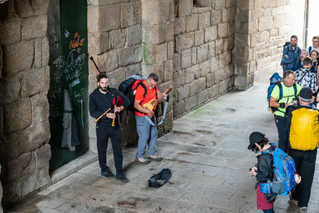 Pilgrims are happy about the bagpipe street musicians, who are not happy at all.