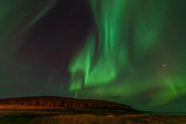 Northern lights over Ekkerøy bird rock at 70 degrees latitude