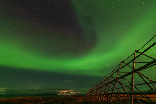 Northern lights over the fish drying racks in Ekkerøy with the rising moon